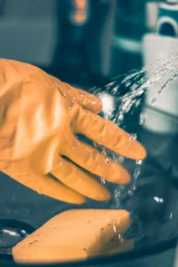 Person in yellow shirt pouring water on clear glass