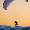 a person is parasailing in the mountains at sunset